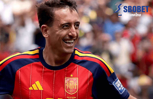 Spanish soccer player in a red Spain jersey smiling on the field; SBOBET logo in the top-right corner.